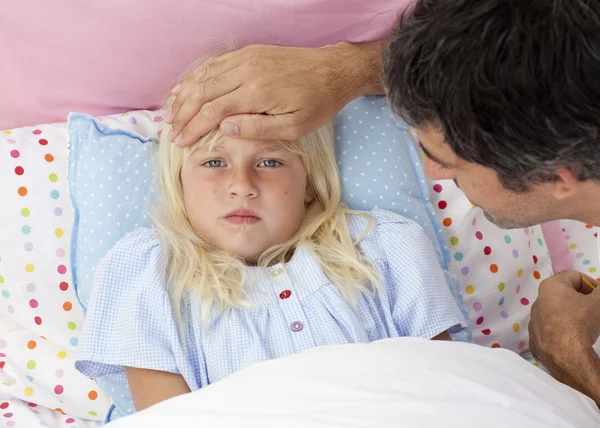 Pai tomando a temperatura de sua filha na cama — Fotografia de Stock