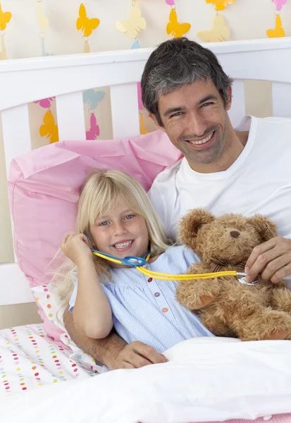 Дочка і тато грають зі стетоскопом і плюшевим ведмедем — стокове фото