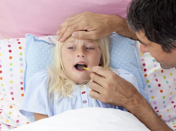 Father checking his daughter's temperature with a thermometer — Stock Photo, Image