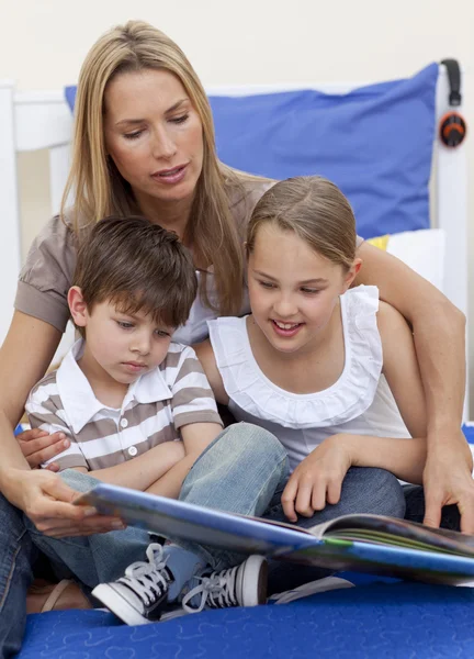 Mutter liest mit ihren Kindern ein Buch — Stockfoto