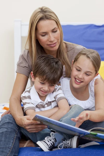 Mutter liest mit Tochter und Sohn ein Buch — Stockfoto