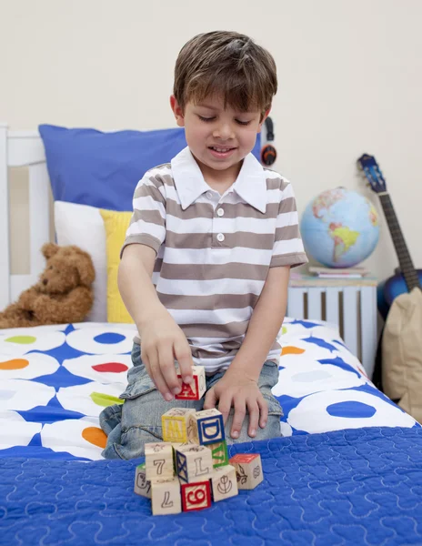 Мальчик играет с кубиками алфавита в своей спальне — стоковое фото