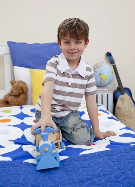 Мальчик играет с поездом в своей спальне — стоковое фото