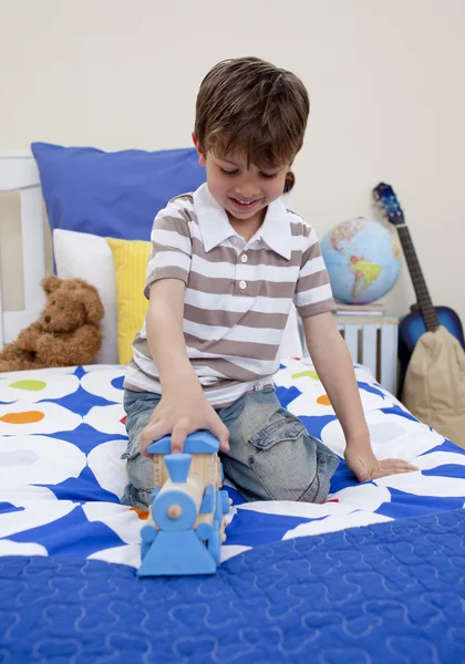 Szczęśliwy chłopiec bawi się kolejką w jego sypialni — Zdjęcie stockowe