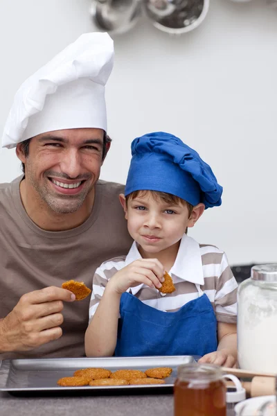 Father and son eating biscuits in the kitchen — Stock Photo, Image