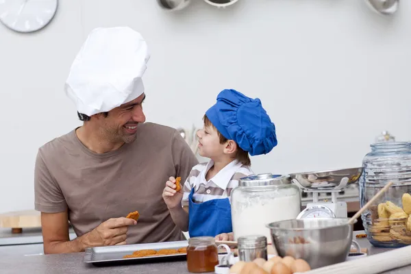 Sorridente padre e figlio mangiare biscotti fatti in casa — Foto Stock