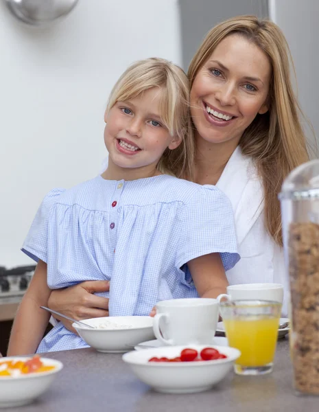 Sorrindo mãe e filha tomando café da manhã juntos — Fotografia de Stock