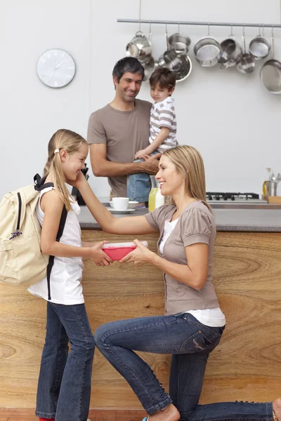 Mother giving girl the school lunch in the kitchen — Stock Photo, Image