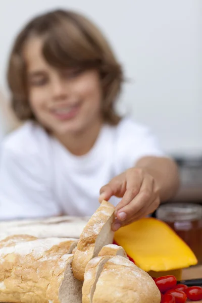Улыбающийся ребенок берет кусок хлеба — стоковое фото