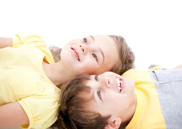 Uśmiechnięte dzieci leżąc na podłodze razem — Zdjęcie stockowe