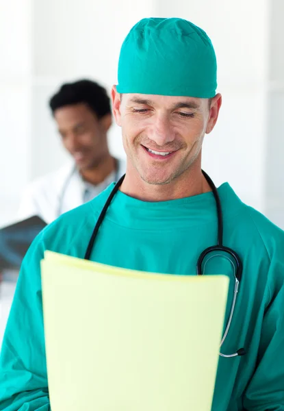 Atrakcyjny chirurg patrząc na pacjenta folderu — Zdjęcie stockowe