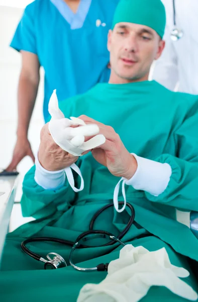 Konzentrierter Chirurg zieht OP-Handschuhe an — Stockfoto