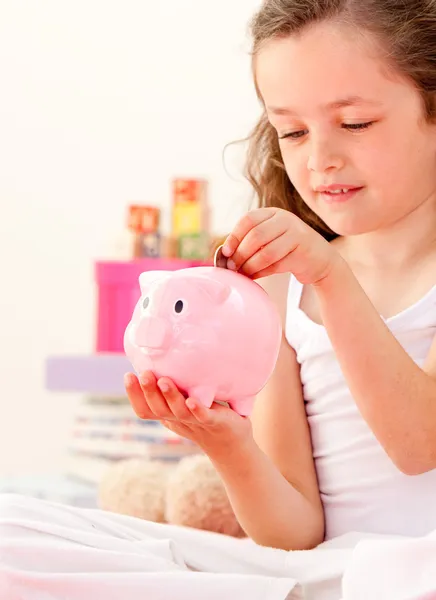 Sevimli küçük kız bir kumbara yatağında oturmuş, para tasarrufu — Stok fotoğraf