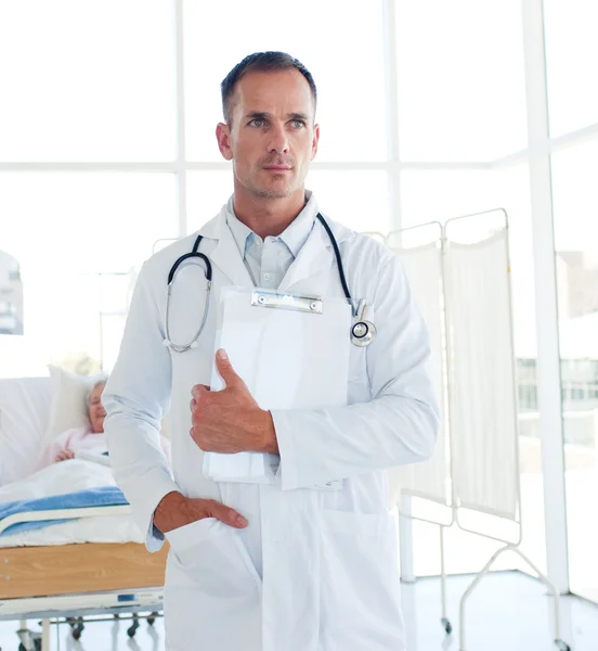 Médico serio sosteniendo un portapapeles médico — Foto de Stock