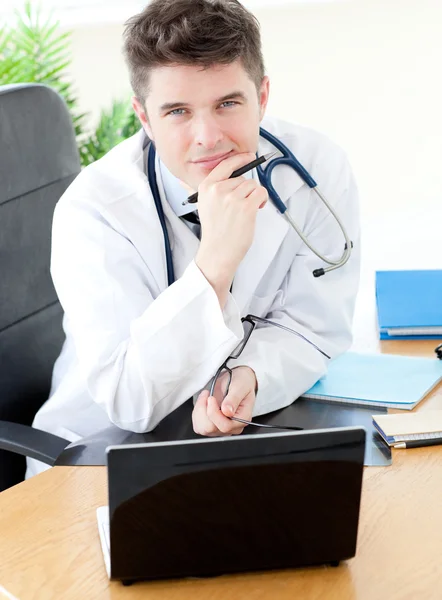 彼の机に座ってラップトップを使用して男性の医師を笑顔 — ストック写真