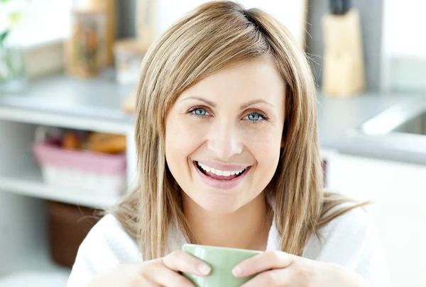 Веселая женщина держит чашку чая на кухне — стоковое фото