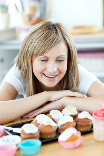 陽気な女性が台所でケーキを見て — ストック写真