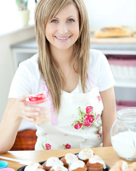 Mulher atraente mostrando bolos na cozinha — Fotografia de Stock
