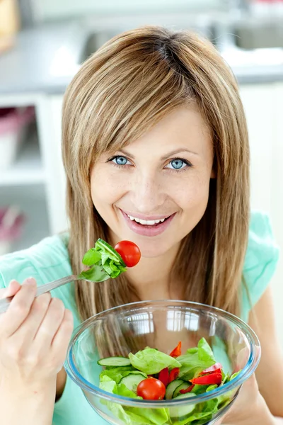Mulher encantada comendo uma salada na cozinha — Fotografia de Stock