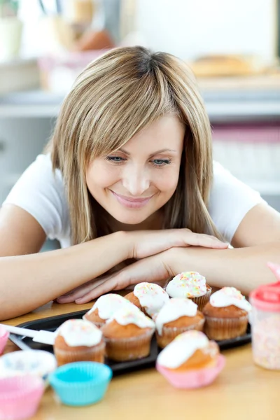 Mulher encantada olhando para bolos na cozinha — Fotografia de Stock