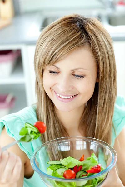 Młoda kobieta jedzenie sałatka w kuchni — Zdjęcie stockowe