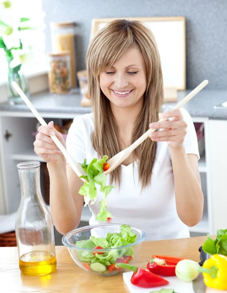 Χαμογελαστή γυναίκα ετοιμάζει μια σαλάτα στην κουζίνα — Φωτογραφία Αρχείου