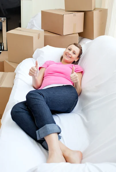Mulher brilhante relaxando em um sofá com caixas — Fotografia de Stock