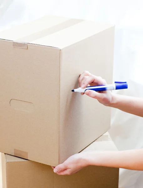 Cute woman writing on a box at home — Stock Photo, Image