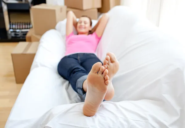 Впевнена жінка розслабляється на дивані з коробками — стокове фото