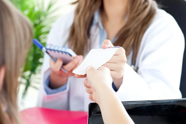 Promienna kobiece lekarz daje papieru do jej pacjenta — Zdjęcie stockowe