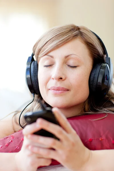 Mulher radiante está ouvindo a música na sala de estar — Fotografia de Stock