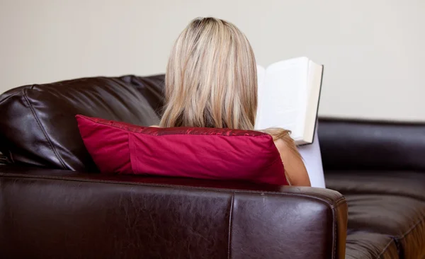 Mladá žena čtení knihy na pohovce — Stock fotografie