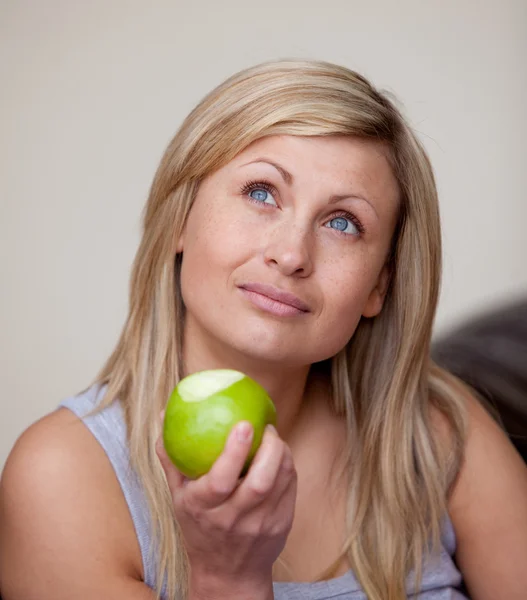 Kaukasische vrouw eten een appel op een sofa — Stockfoto