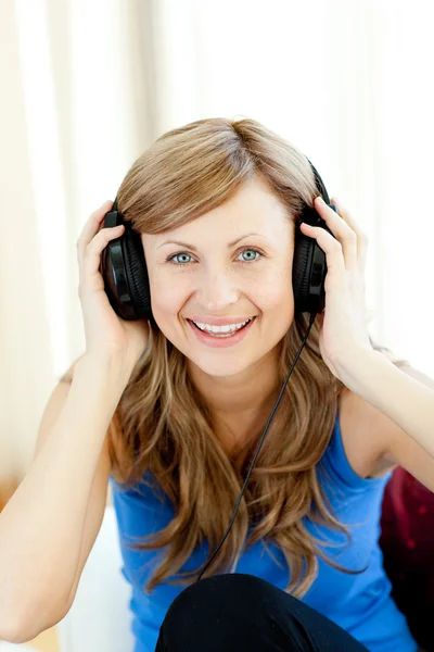 Usmívající se žena poslouchá hudbu v obývacím pokoji — Stock fotografie