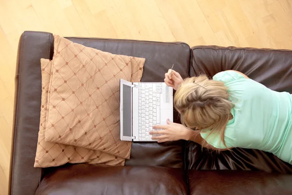 明亮女人在沙发上使用一台笔记本电脑 — 图库照片