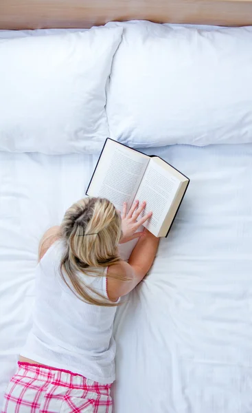 Καυκάσιος γυναίκα διαβάζοντας ένα βιβλίο σε ένα κρεβάτι — Φωτογραφία Αρχείου