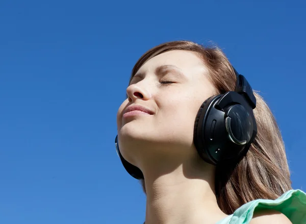 Mujer linda está escuchando música al aire libre — Foto de Stock