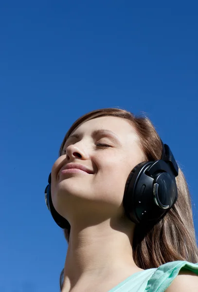 Mulher bonita está ouvindo música ao ar livre — Fotografia de Stock