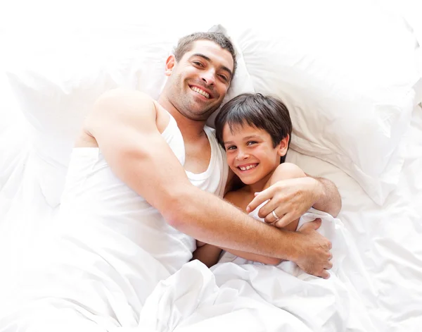 Charming father and his son looking at the camera on the bed Stock Picture