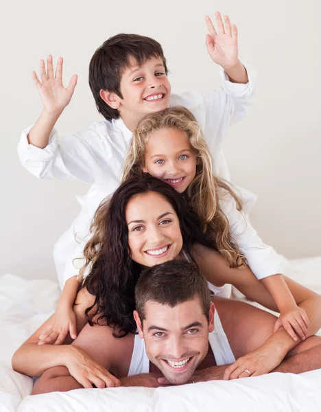 Веселая семья веселится вместе на кровати — стоковое фото