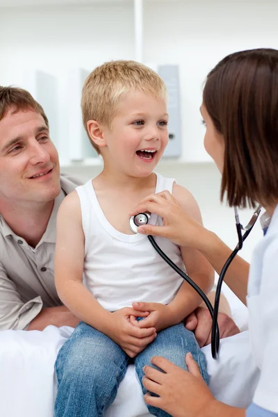 Female doctor examining a boy with his father in tow — Stock Photo, Image
