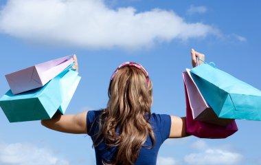 Happy woman holding shopping bags outdoor clipart