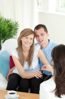 Jolly young couple receiving their new car's key clipart