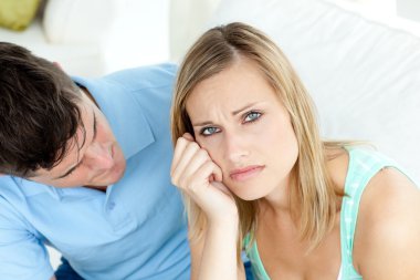 Sad couple having an argue in the living-room clipart