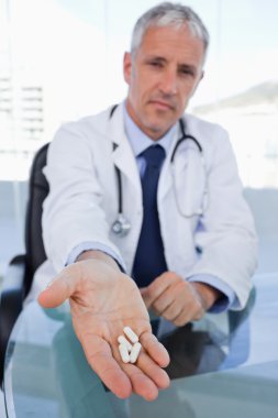 Portrait of a doctor showing pills clipart