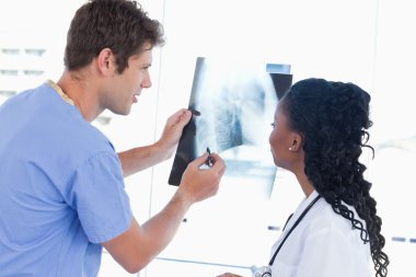 Young doctors looking at a of X-ray in an office clipart