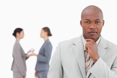 Thinking businessman with colleagues behind him clipart