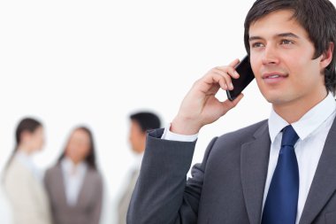 Salesman on his cellphone with team behind him clipart