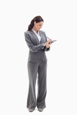 Businesswoman focusing and writing on a clipboard clipart