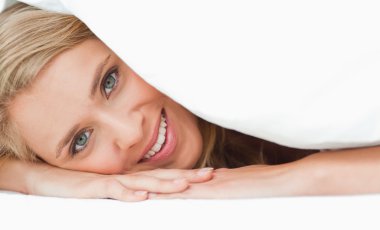 Close up, Woman under a quilt, her hands under her head,smiling clipart